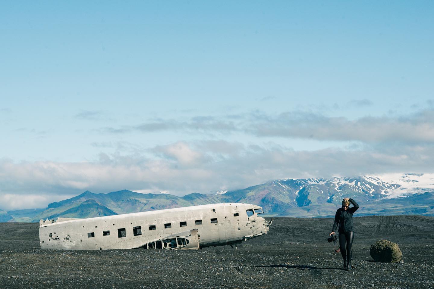 Photographer standing beside the DC-3 plane wreck on the black sand beach at Solheimasandur, Iceland