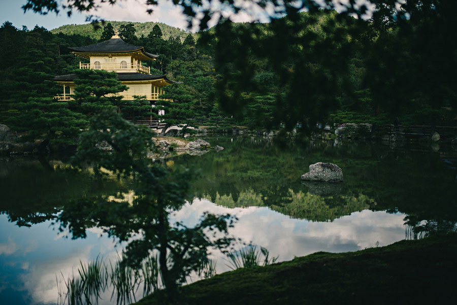 Kinkaku-ji Golden Pavilion reflected in a still pond surrounded by lush green gardens in Kyoto