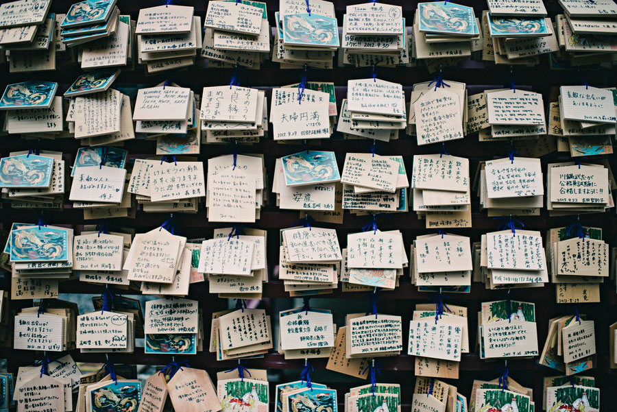 Rows of wooden ema prayer tablets covered in handwritten wishes at a Japanese shrine