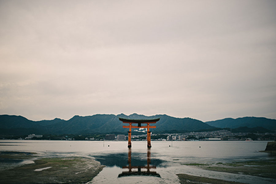 Floating torii gate of Itsukushima Shrine standing in the tidal flats with mountains behind