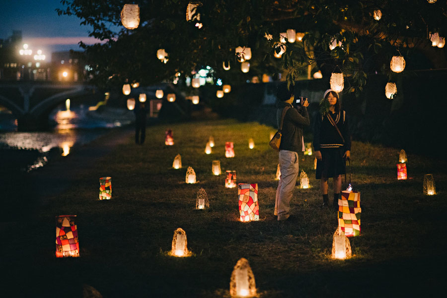 Paper lanterns scattered across a riverbank park at night during a lantern festival in Hiroshima