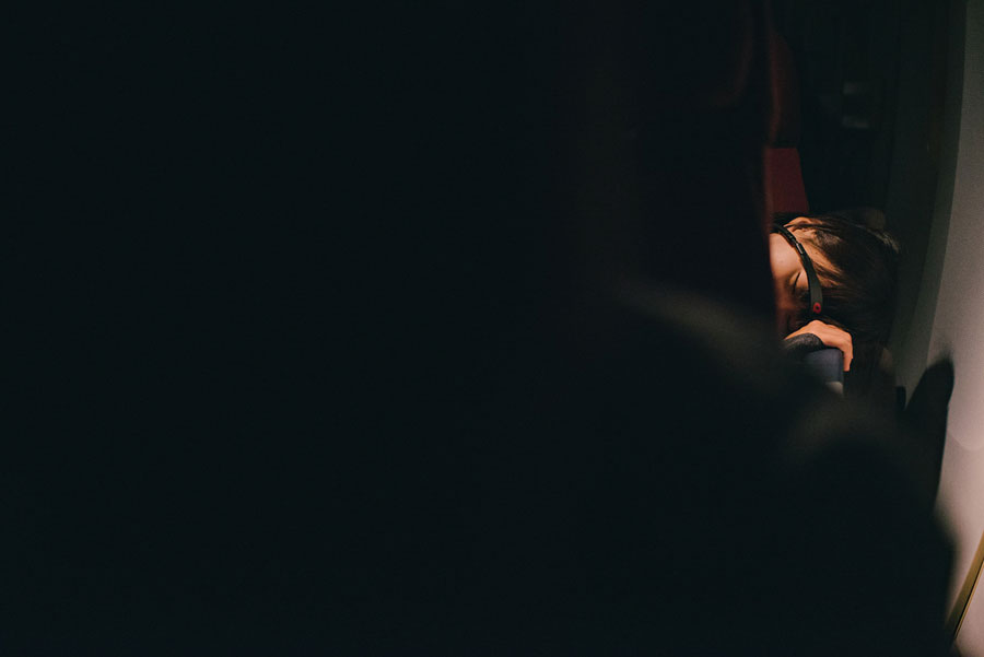 Person sleeping in near-total darkness with only a sliver of light across their face