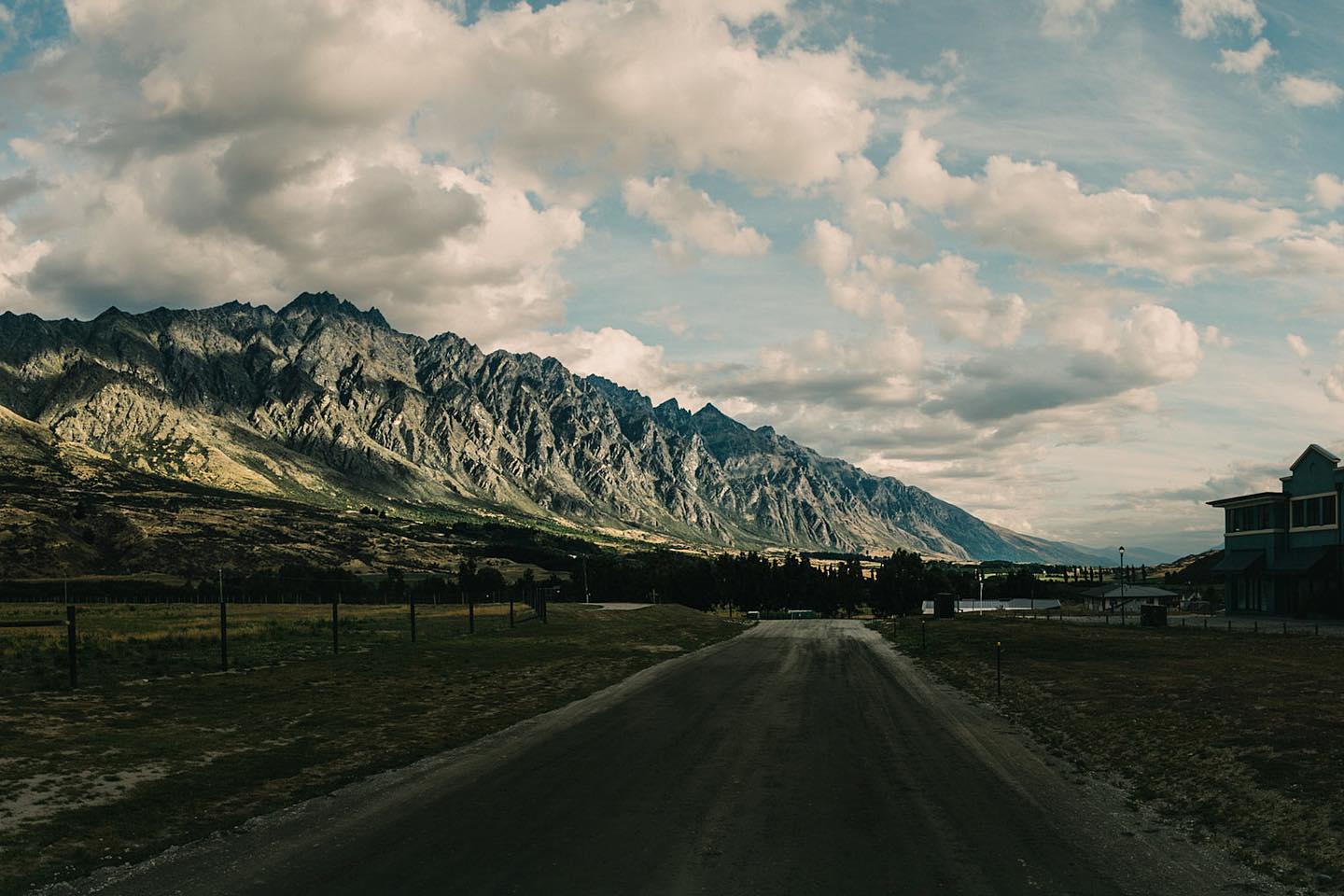 Wide view of the Remarkables mountain range across open countryside near Queenstown, New Zealand